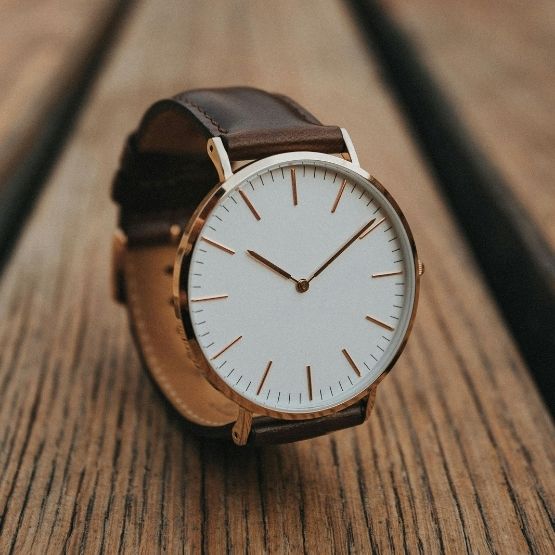 Montre au bracelet en cuir marron posée sur une surface en bois.