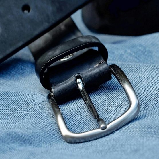 Close-up of a leather belt buckle on a pair of jeans.