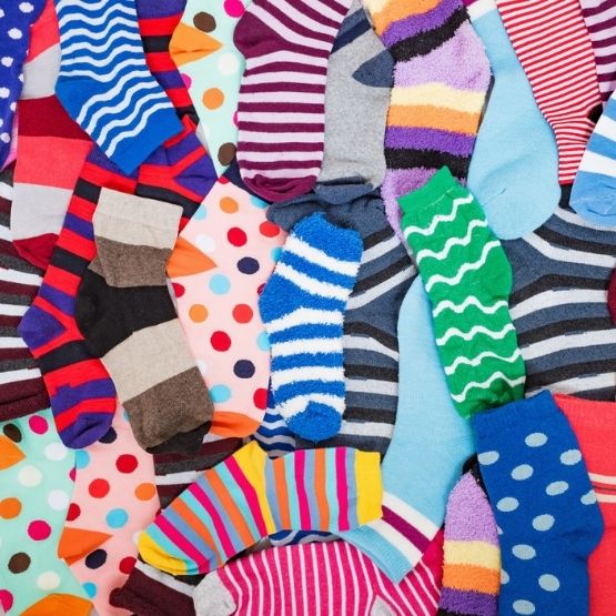 A set of colourful socks in a variety of patterns spread over a surface.