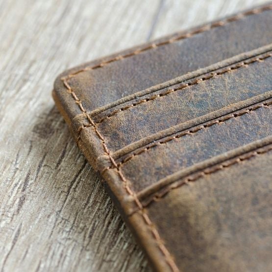 Porte-cartes en cuir marron vieilli sur fond en bois.