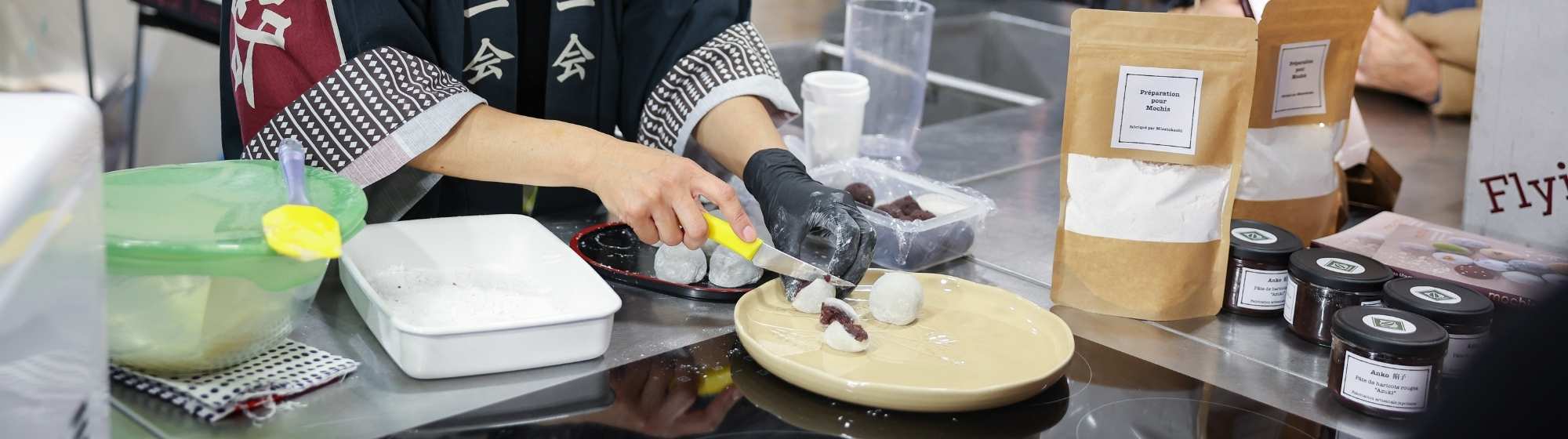 Atelier de cuisine créative sur un salon, avec une animatrice préparant une recette sur une plaque devant le public