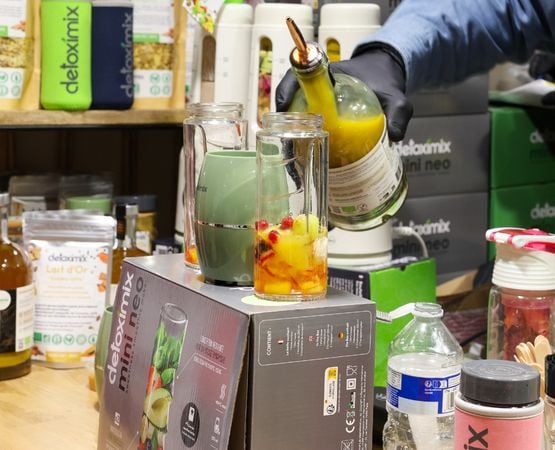 Préparation d’un cocktail sans alcool à base de fruits dans un blender, présentée sur un stand de démonstration