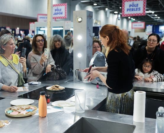 Démonstration culinaire en direct lors d’un salon créatif, avec une animatrice préparant une recette devant le public