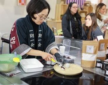 Atelier de cuisine créative sur un salon, avec une animatrice préparant une recette sur une plaque devant le public