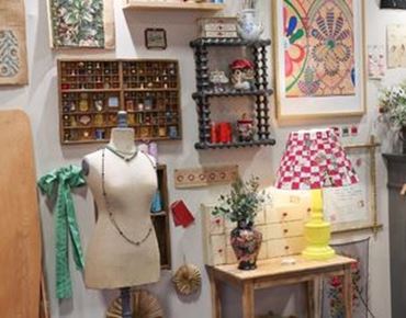 Atelier de creation avec mannequin de couture, objets decoratifs vintage, etagere murale et lampe coloree dans un espace artisanal.