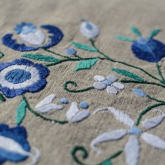 Blue floral embroidery on beige canvas, visible stem stitch