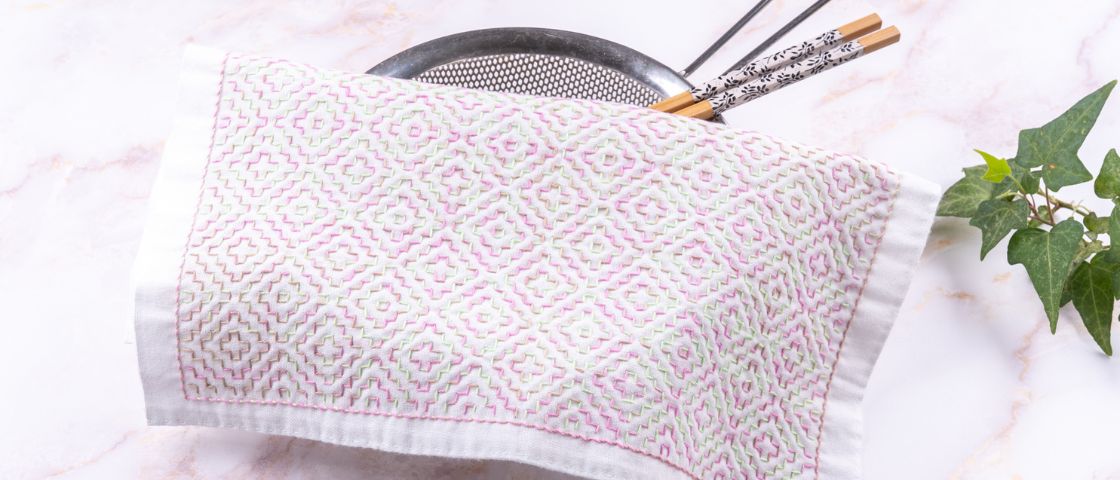 Hands sewing black fabric with sewing tools in background