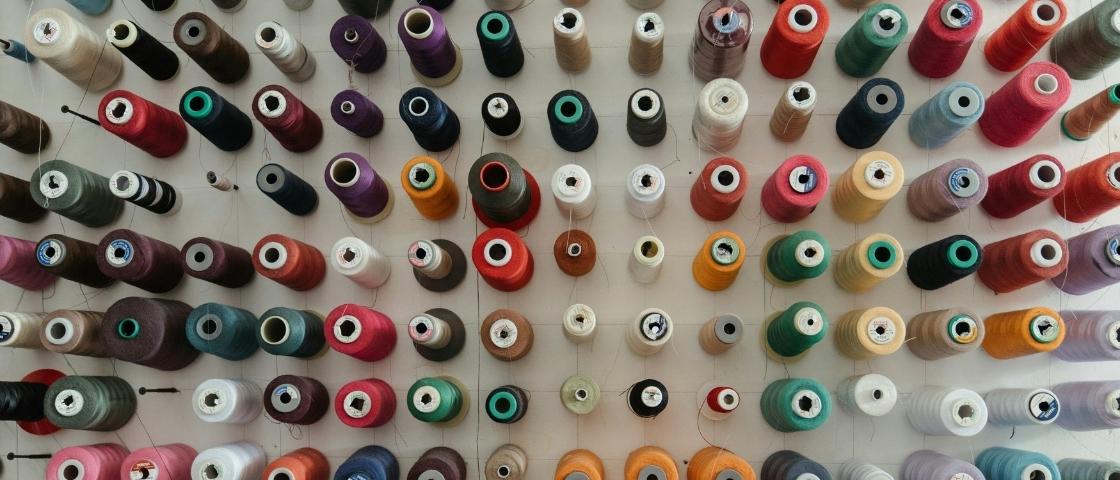 Spools of yarn of various colours hanging on a wall
