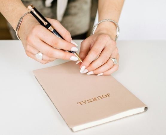 Personne écrivant dans un carnet pour commencer un bullet journal créatif