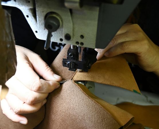 Artisan cousant du cuir à la machine dans un atelier.