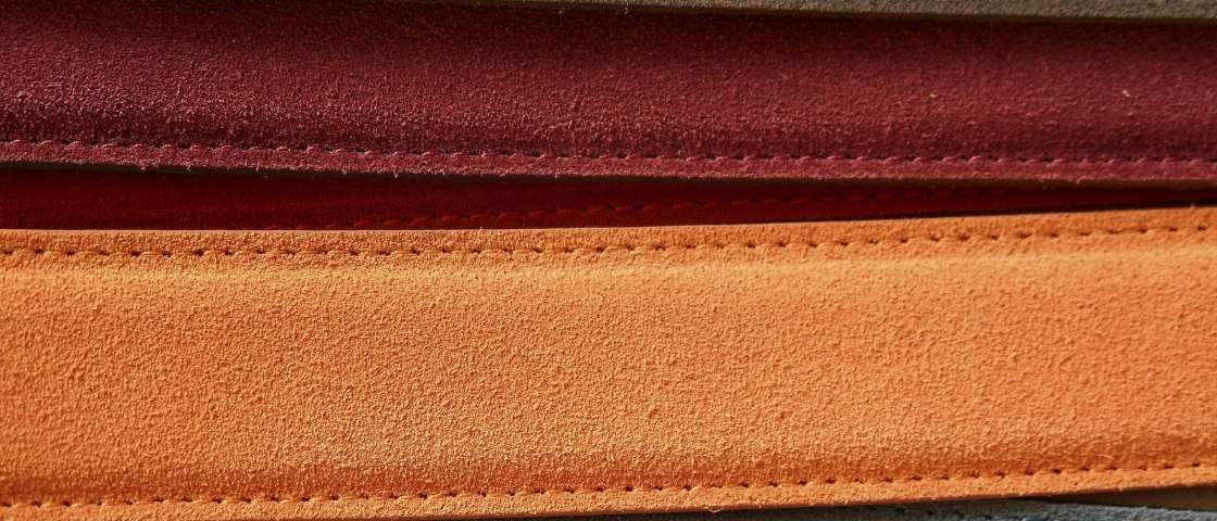 Détails de coutures sur bandes de cuir de différentes couleurs.