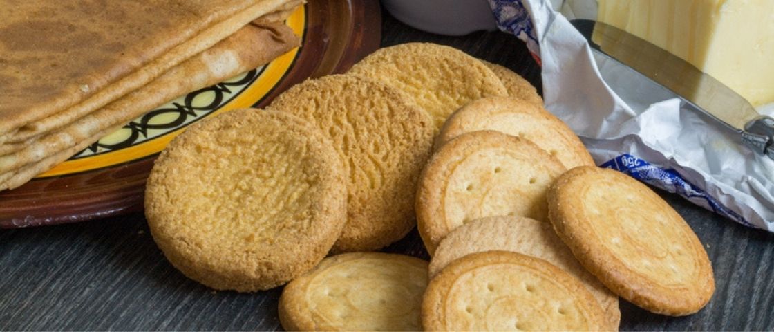 Assortiment de biscuits sablés et crêpes posés sur une table avec du beurre.