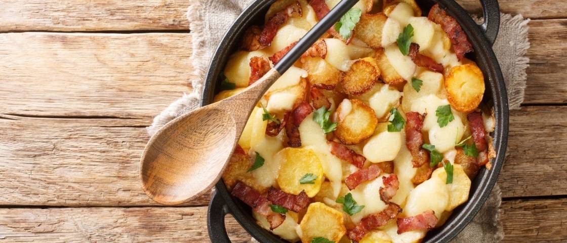 Plat de truffade au fromage, pommes de terre et lardons présenté dans une poêle en fonte.
