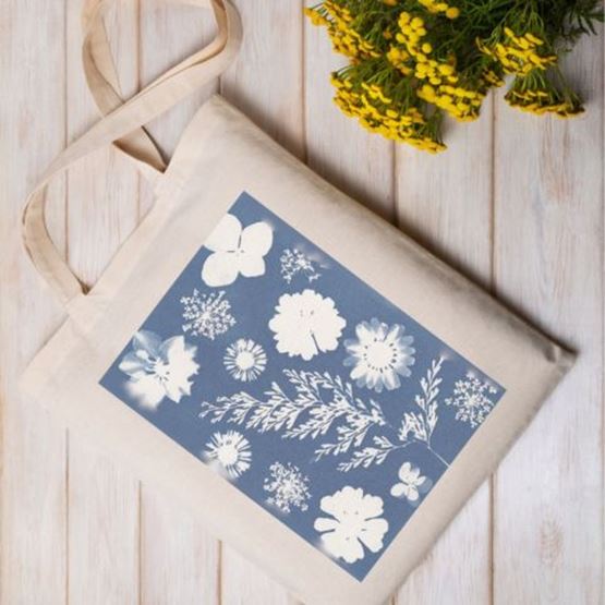 Beige tote bag decorated with a cyanotype motif of white flowers on a blue background.
