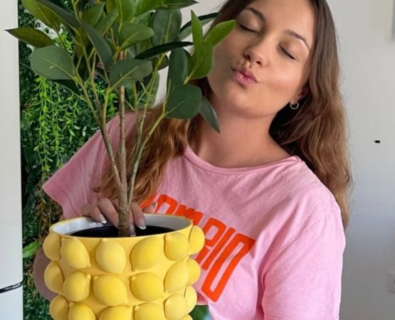 Woman holding a textured yellow planter with a green plant in a DIY decorating environment