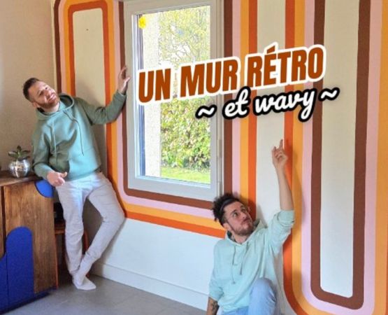 Couple in front of a retro wall painted with orange and brown wavy stripes