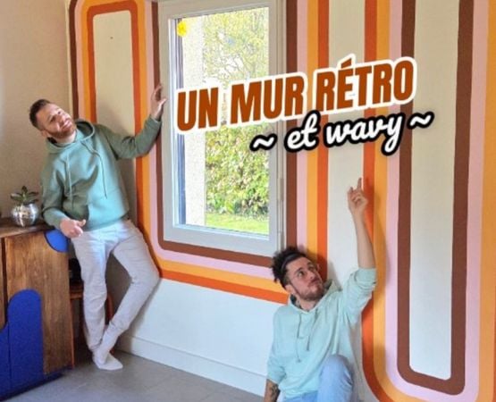 Couple devant un mur rétro peint avec rayures wavy orange et marron