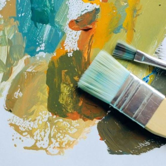 Brushes resting on patches of multicoloured gouache paint.