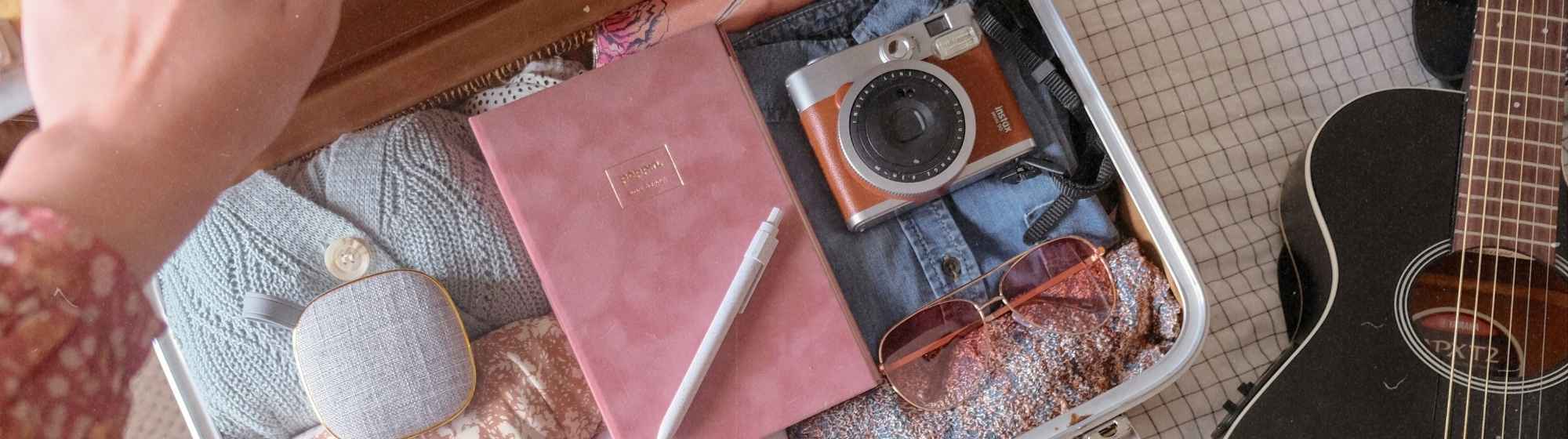 Open suitcase containing travel accessories and a camera