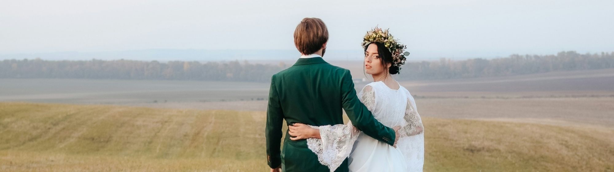 married couple walking in field wedding field white dress wreath of flowers landscape nature