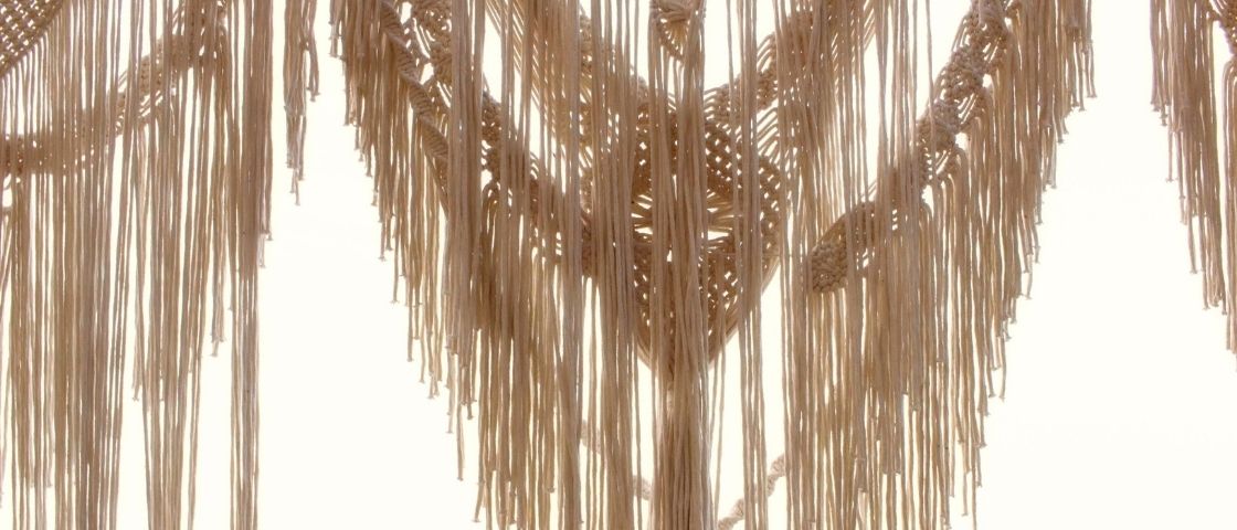 Hanging lamp in macramé with long fringes in beige cotton.