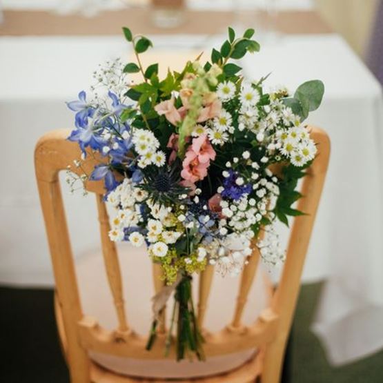 Country bouquet tied to the back of a wooden chair for a wedding.
