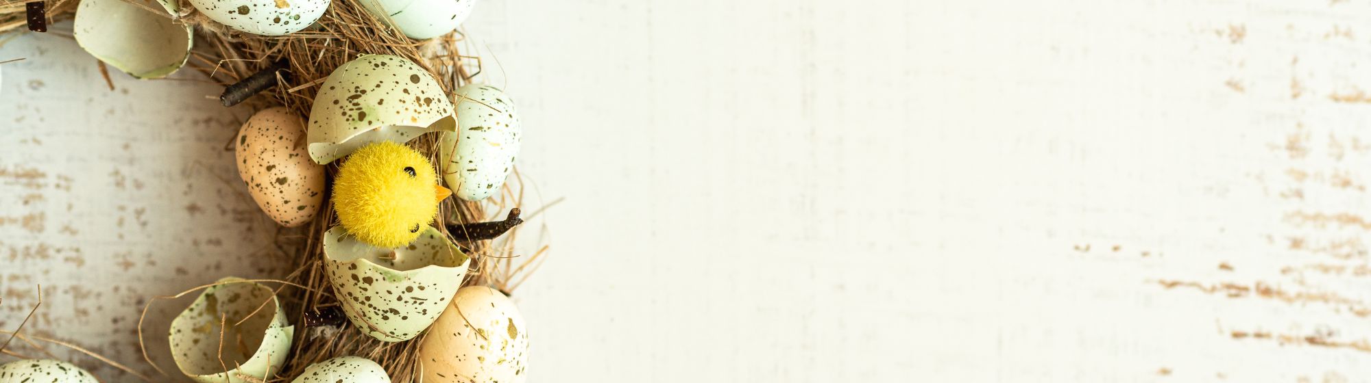 Easter wreath decorated with spotted eggshells and small yellow chicks.