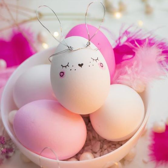 Easter egg decorated like a rabbit with drawn lines and wire ears.