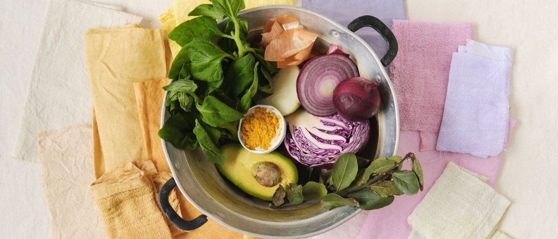 Natural ingredients for textile dyeing in a saucepan with coloured fabrics.