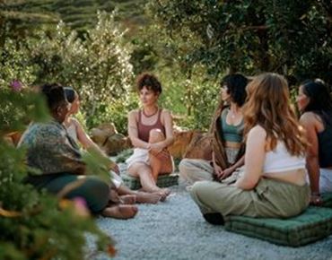 Groupe de femmes assises en cercle en extérieur lors d’un atelier de discussion et de développement personnel.