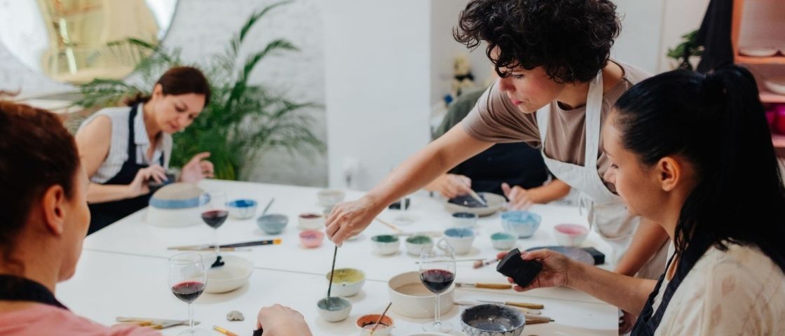 Collective creative workshop with participants painting and mixing pigments around a table.