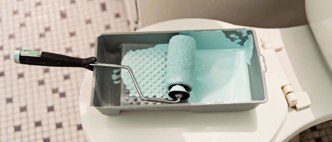 Rouleau et bac de peinture utilisés pour peindre du carrelage de salle de bain.