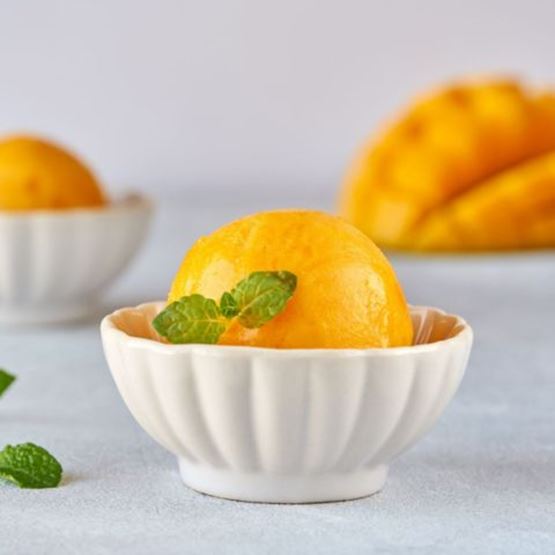 Mango sorbet served in a small white dish with mint leaves.