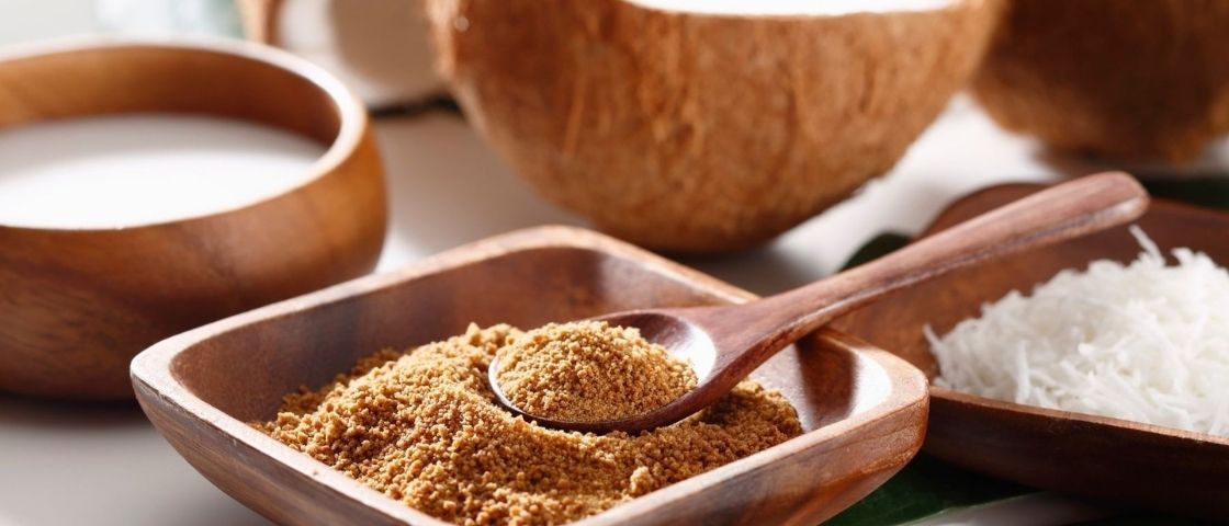 Coconut powder, coconut milk and coconut shavings in wooden bowls.