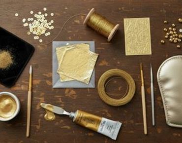 Outils et matériaux utilisés pour la dorure artisanale, avec feuilles d’or, pinceaux et pigments.