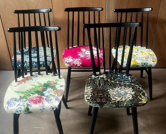 Five black chairs with colourful seats and floral patterns