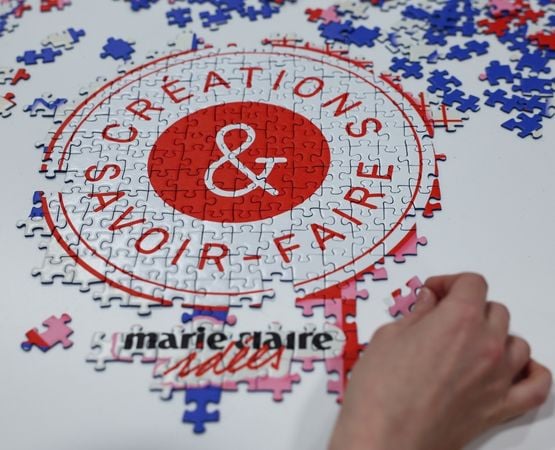 Puzzle en cours d’assemblage avec le logo « Créations & Savoir-faire » et une main positionnant une pièce.