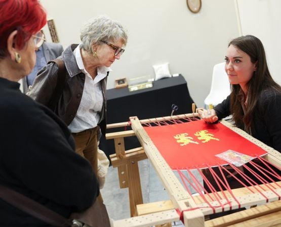 Atelier de tissage avec démonstration sur métier à tisser devant des visiteurs.