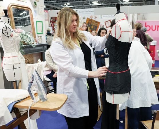 Démonstration de couture sur mannequin lors d’un atelier avec une professionnelle ajustant un vêtement.
