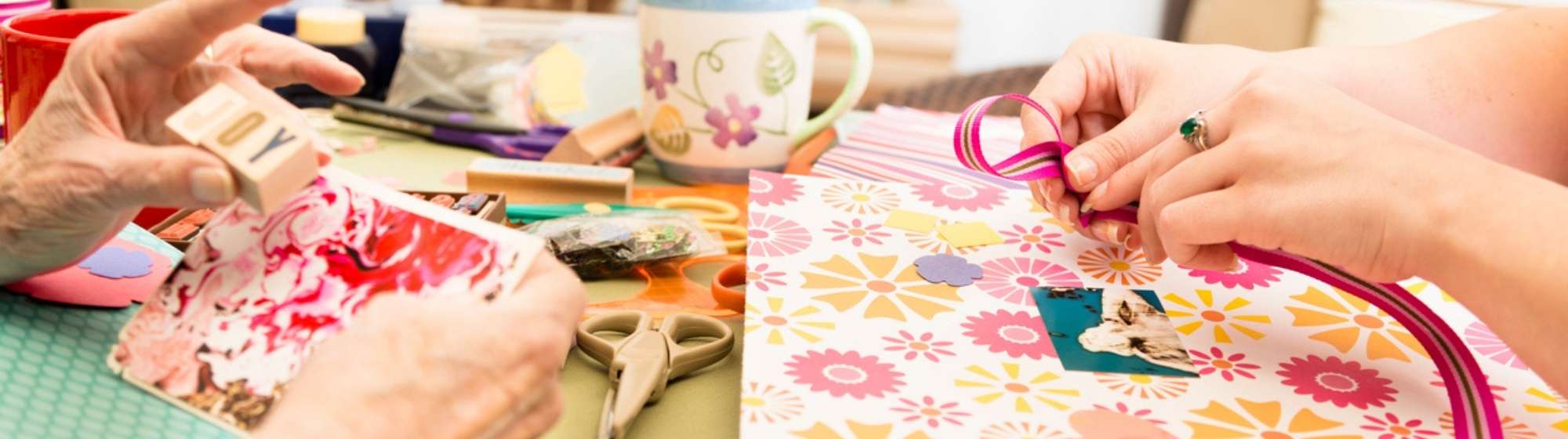 Scrapbooking workshop with two people gluing and decorating coloured paper.