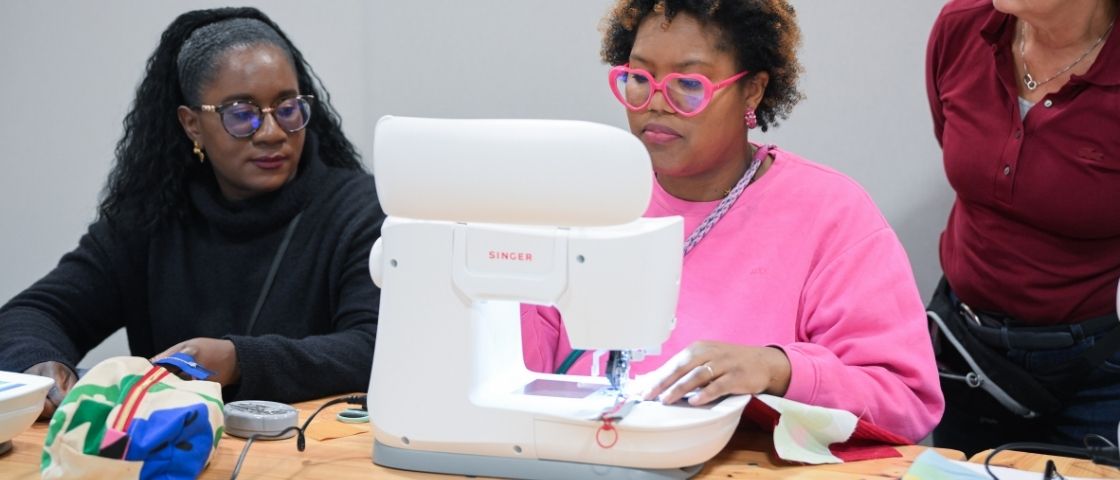 Visiteuse participant à un atelier de couture avec une machine à coudre