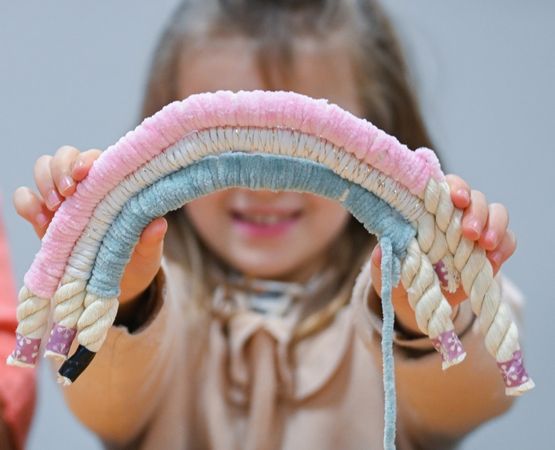 Enfant présentant une création artisanale en forme d'arc-en-ciel