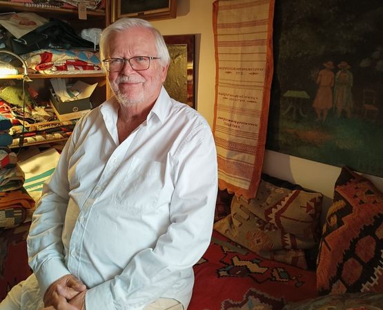 Portrait d'un homme en chemise rose souriant légèrement.