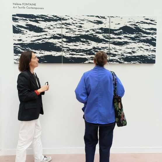 Woman observing works of textile art in a gallery.
