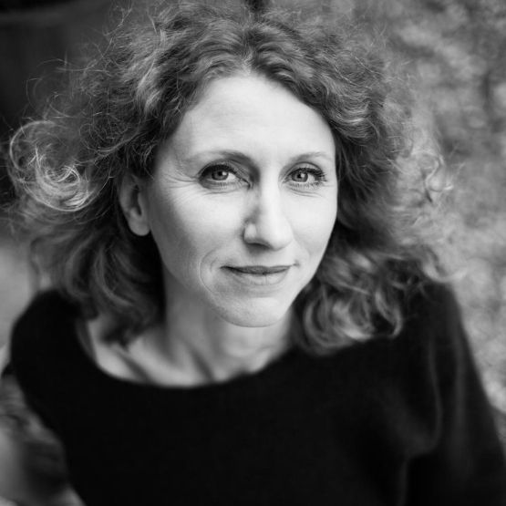 Black and white portrait of a woman with curly hair smiling gently.