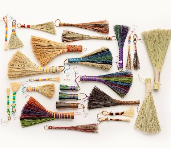 Collection of colourful handmade brooms in various sizes.