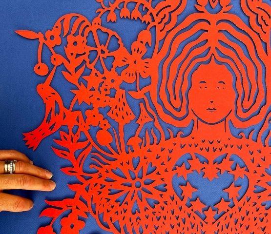 Red paper cut-out showing a female face surrounded by flowers.