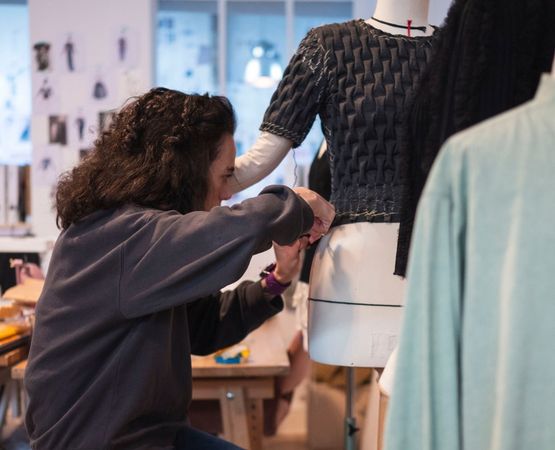 Professionnelle ajustant un vêtement sur un mannequin lors d'un atelier de couture Artesane