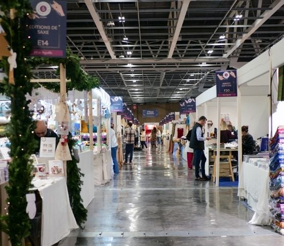 View of a trade show with decorated stands and clear signage indicating aisles and areas.