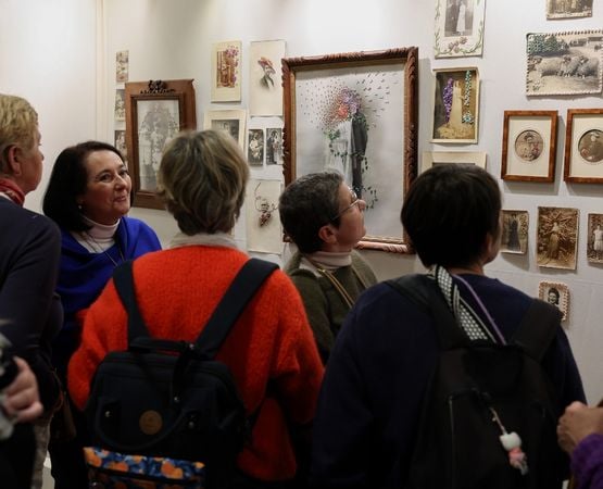 Visiteuse observant des œuvres abstraites encadrées lors d’une exposition d’art contemporain dans une galerie